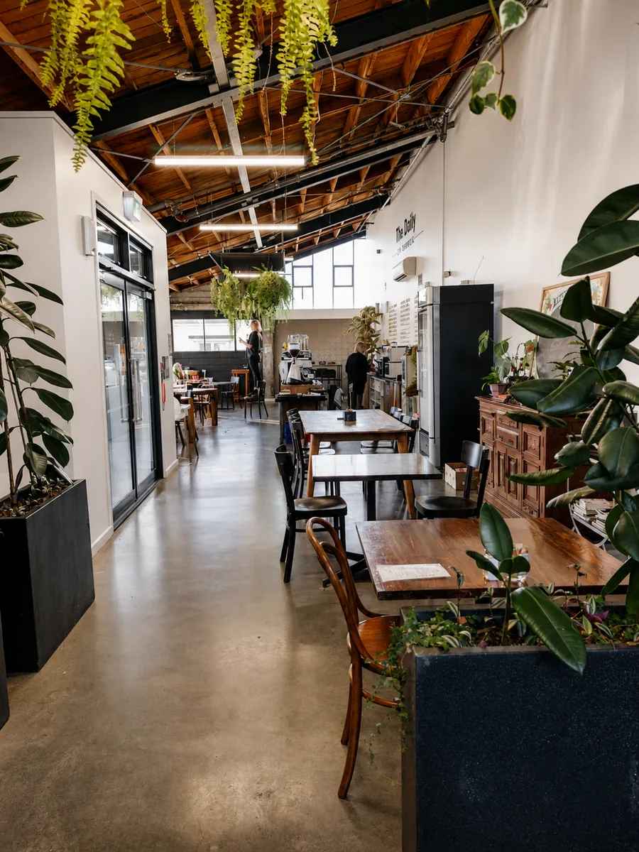 Timber beams, hanging ferns and tables inside the cafe